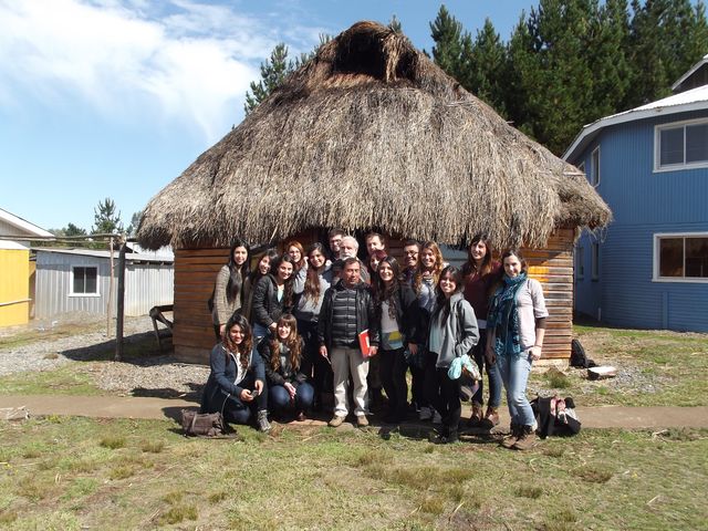 Los estudiantes de terapia ocupacional posan con el chamán jefe (pantalones blancos) frente a la "ruca", (casa tradicional mapuche), que en el "Centro" se usa como sala de reuniones y aula.