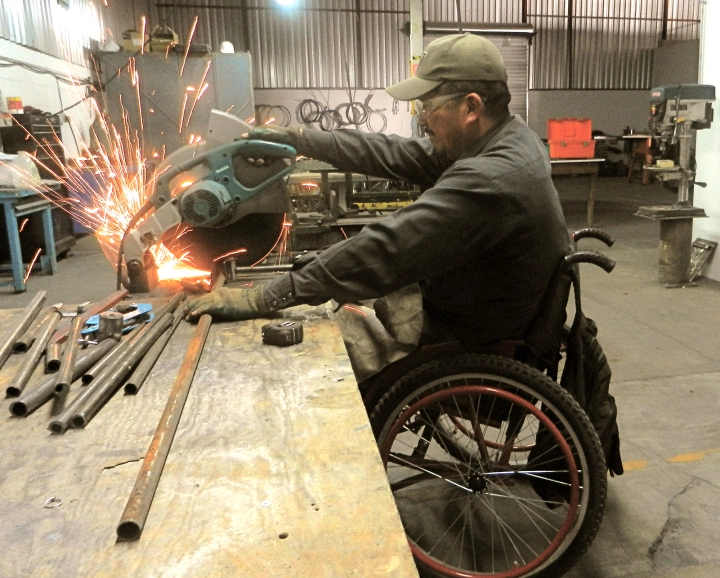 Gabriel en el taller de ARSOBO: corta tubos para hacer una silla de ruedas.