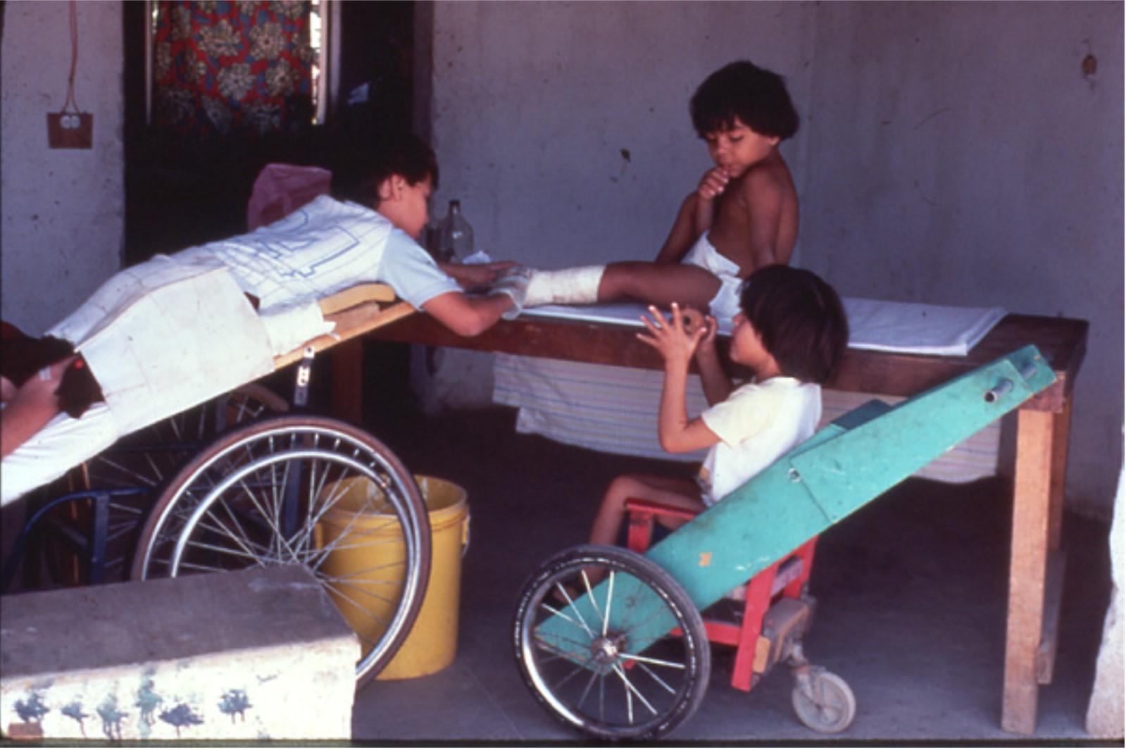 En PROJIMO, personas con discapacidad se atendían unas a otras. Aquí una niña paralizada por un balazo cura las escaras (llagas) de una niña con espina bífida.