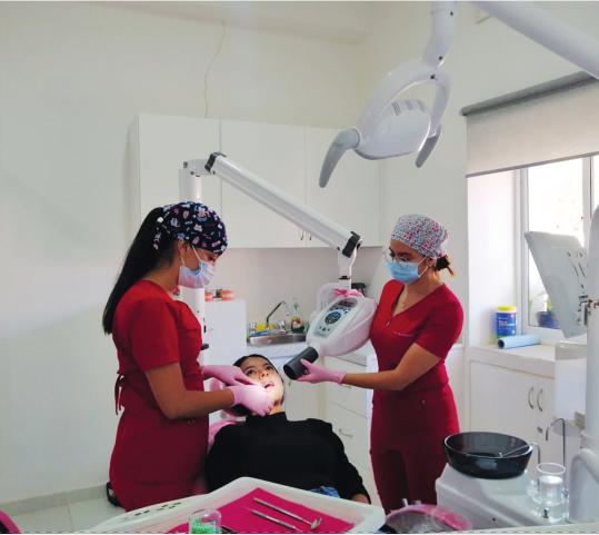 Las doctoras Olga Vanessa Vega (Izq.) y Elisa Peña Bastidas (Der.), ambas cirujanas dentistas, atendiendo a una paciente en el consultorio dental de la Clínica de Ajoya. Olga es hija del Dr. Renán, y ambas provienen de familias oriundas de la comunidad.