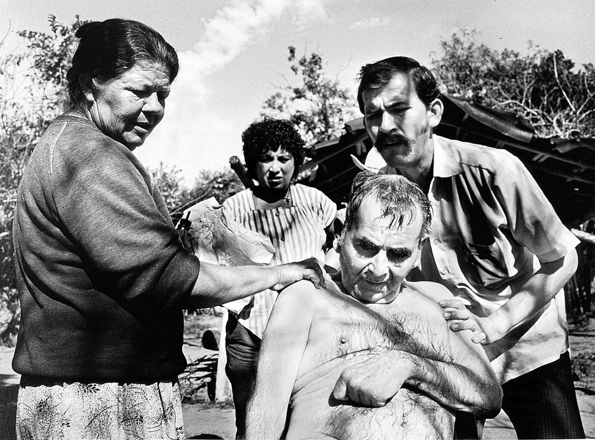 Los trabajadores de la salud de la aldea bañan a un hombre paralizado por un derrame cerebral.