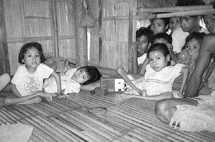 In their bamboo hut, Mercy, Rosalie and Jenny meet with visitors from SLF, while curious village children look on.