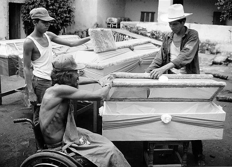 Mario (foreground) with the help of Martin (who has had chronic asthma since childhood) and Sergio put the finishing touches on a batch of cloth-covered wooden coffins.