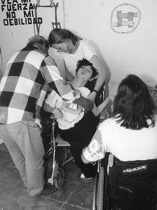 Xochi, a girl whose asymetrical spasticity from cerebral palsy has caused a fixed spinal curve and wind-swept legs, presented a big challenge for seating. Here her father and Jean Anne Zollars try to position her in her wheelchair.