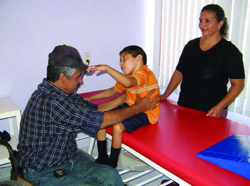 Raymundo evaluates a child for a wheelchair. The fact that those who design and make the chairs are themselves disabled provides an excellent role model for the children needing wheelchairs.