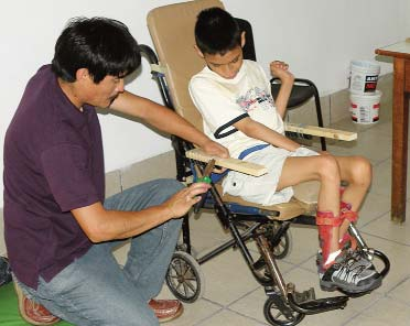 Max’s older brother was a big help at the workshop. Here he extends the armrests of Max’s wheelchair, to support a tray.