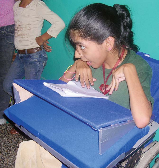 Workshop participants in Peru adapted Ada’s wheelchair to better meet her needs, adding a special backrest, cushion, and a table with an adjustable stand for better hand control.