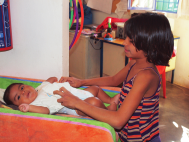 A young girl changes the diapers of a recent arrival at the Shelter.