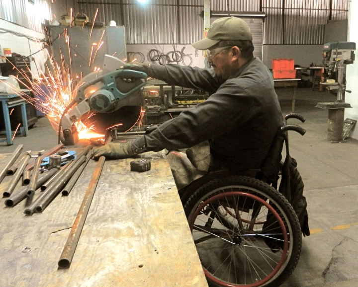 Gabriel in the ARSOBO workshop cutting tubes to make a wheelchair.