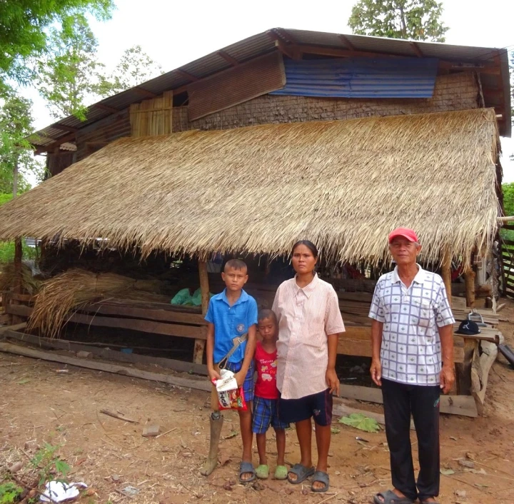 Arm wearing his artificial leg—with his mother, little brother, mother and stepfather—outside their home.