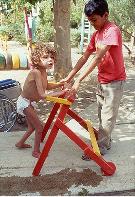 Some members of the group rebuilding Ajoya, long ago as schoolkids there, used to enjoy helping out at PROJIMO. Here a schoolboy, who helped make this walker, teaches a disabled child to take his first steps.