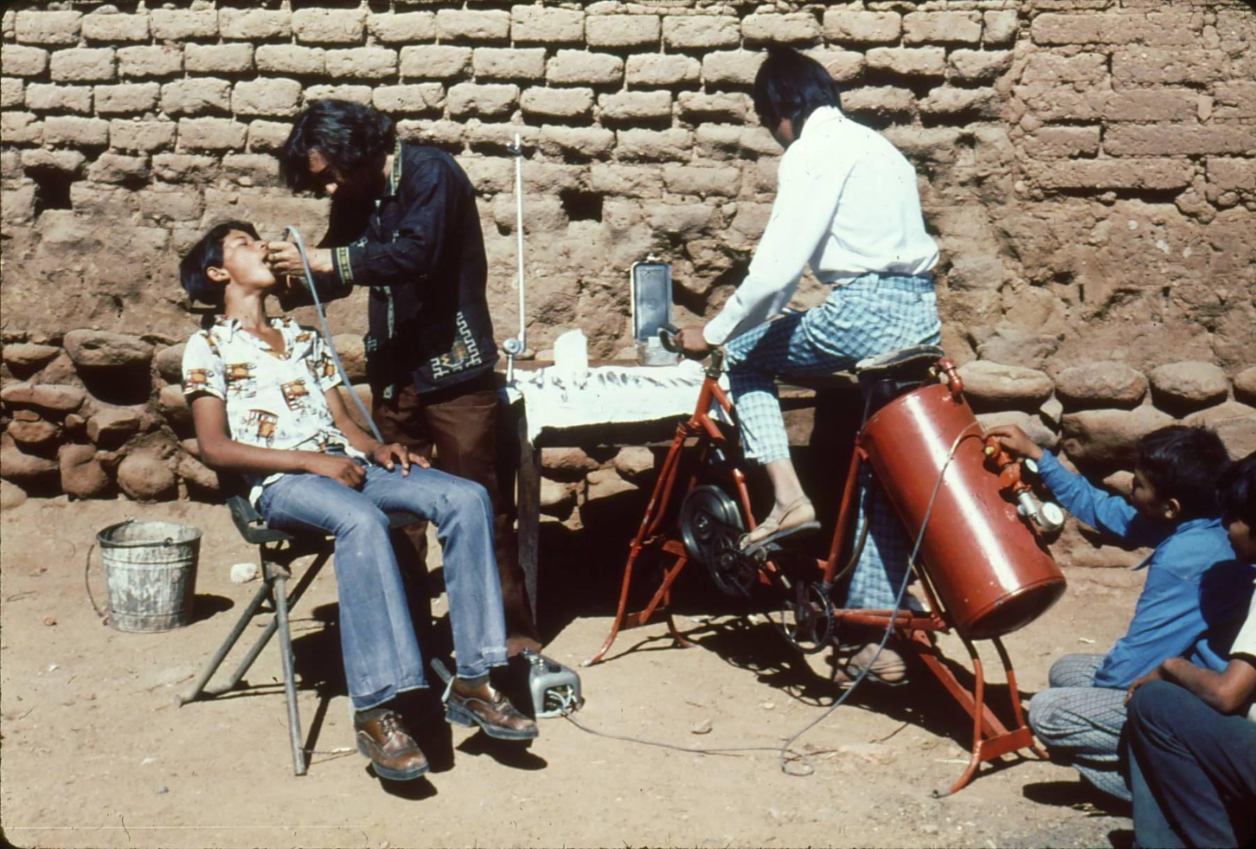 In times past, the old villager-run health post in Ajoya also provided dental services---less elegantly but well adapted to the local reality. This young villager, Miguel Ángel Manjarrez, began pulling teeth at age 13. Here he drills out a cavity using a modern air-powered drill, whose compressor tank is pumped up with a bicycle. This equipment can be carried on muleback, to drill and fill teeth in remote ranchos without electricity.